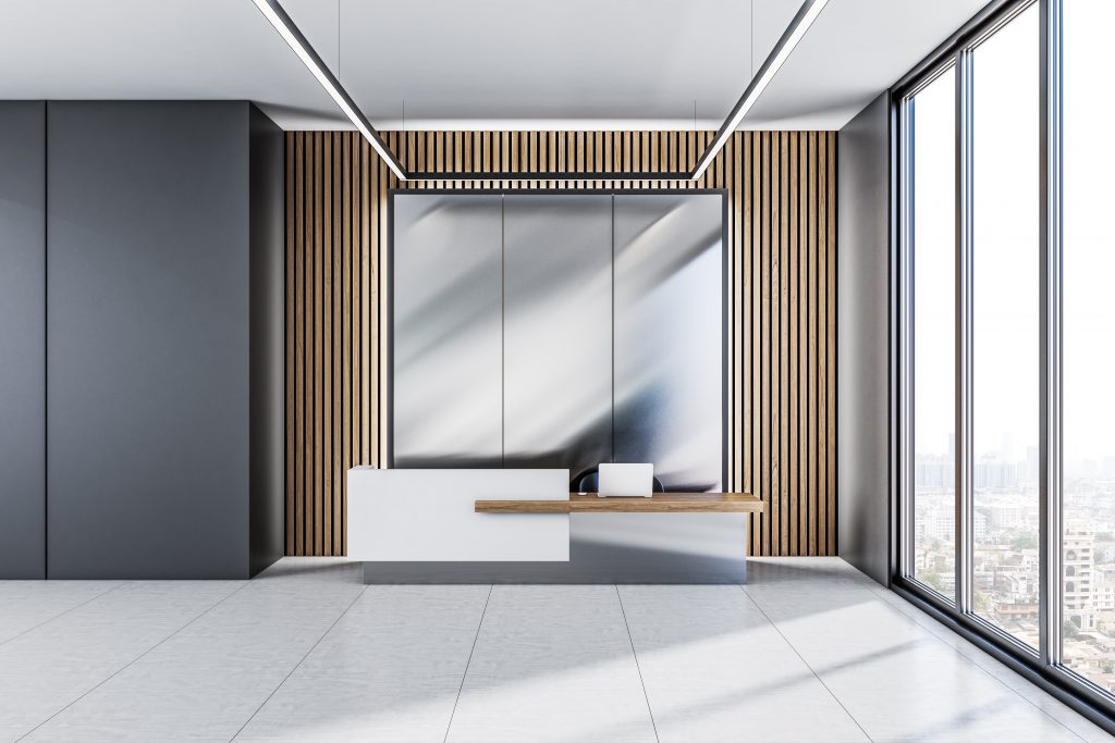 front view on stylish on reception desk in sunlit spacious office area with wooden slatted wall, light grey ceramic floor and city view from panoramic window. 3d rendering